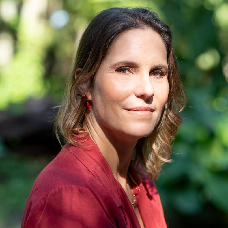 foto de Tatiana Botelho, com cabelos medios e loiro escuro, olhando diretamente para a câmera.